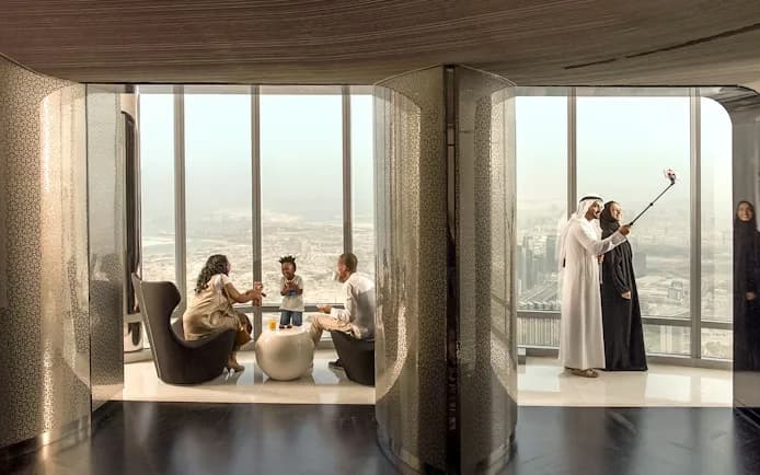 Guests seated in the SKY 148 lounge beside a floor to ceiling window high above Dubai