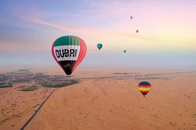 A Dubai branded hot air balloon over the desert at sunrise with other balloons behind