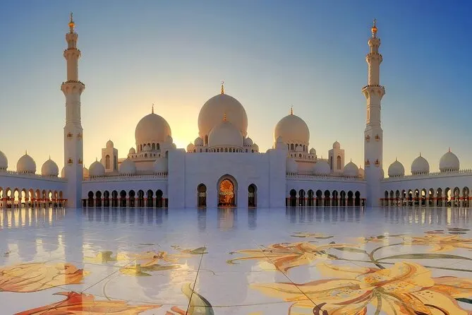 Sheikh Zayed Grand Mosque at sunset, reflected in the wet marble of the courtyard